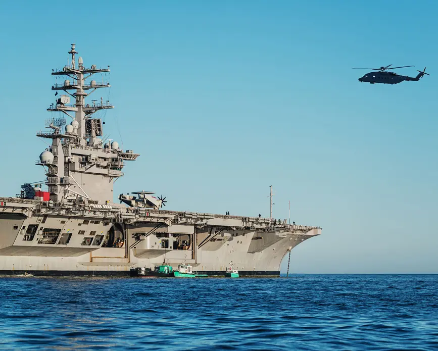 Warship and helicopter under clear sky